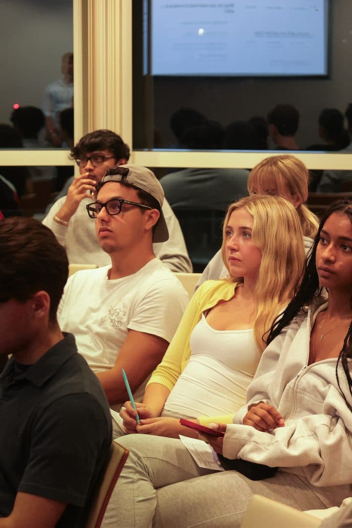 Students in the audience, one with a pen and an index card in hand.